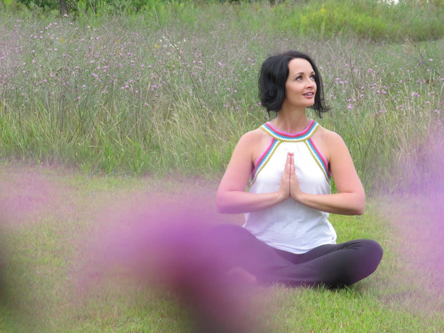 Flora Sage meditating in a wildflower meadow